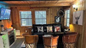 Ein gemütliches Blockhaus-Interieur mit Holzausstattung, einer Ledersofa und rustikalen Sesseln.