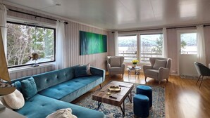A spacious living room with a large sectional sofa, a coffee table, and two armchairs. - La Casa Senja Seaview Villa with Sauna (Troms)