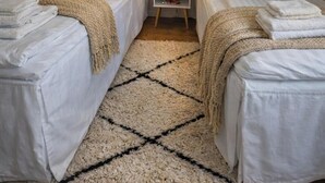 A hotel room with two single beds, a small bedside table with a lamp, a mirror, and a rug. - La Casa Senja Seaview Villa with Sauna (Troms)