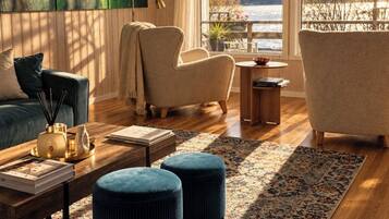 Ein modernes Wohnzimmer mit Seeblick und Bergblick, ausgestattet mit einer Couch, Sesseln, einem Couchtisch und einem gemusterten Teppich.