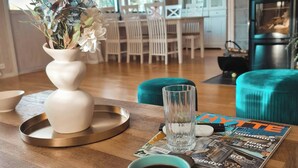 A modern living room with a wooden coffee table, a vase of flowers, a coffee cup, and a magazine. - La Casa Senja Seaview Villa with Sauna (Troms)