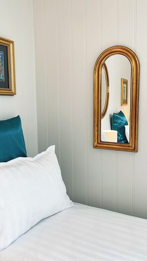 A hotel room with a bed, a large mirror, and a framed picture on the wall.