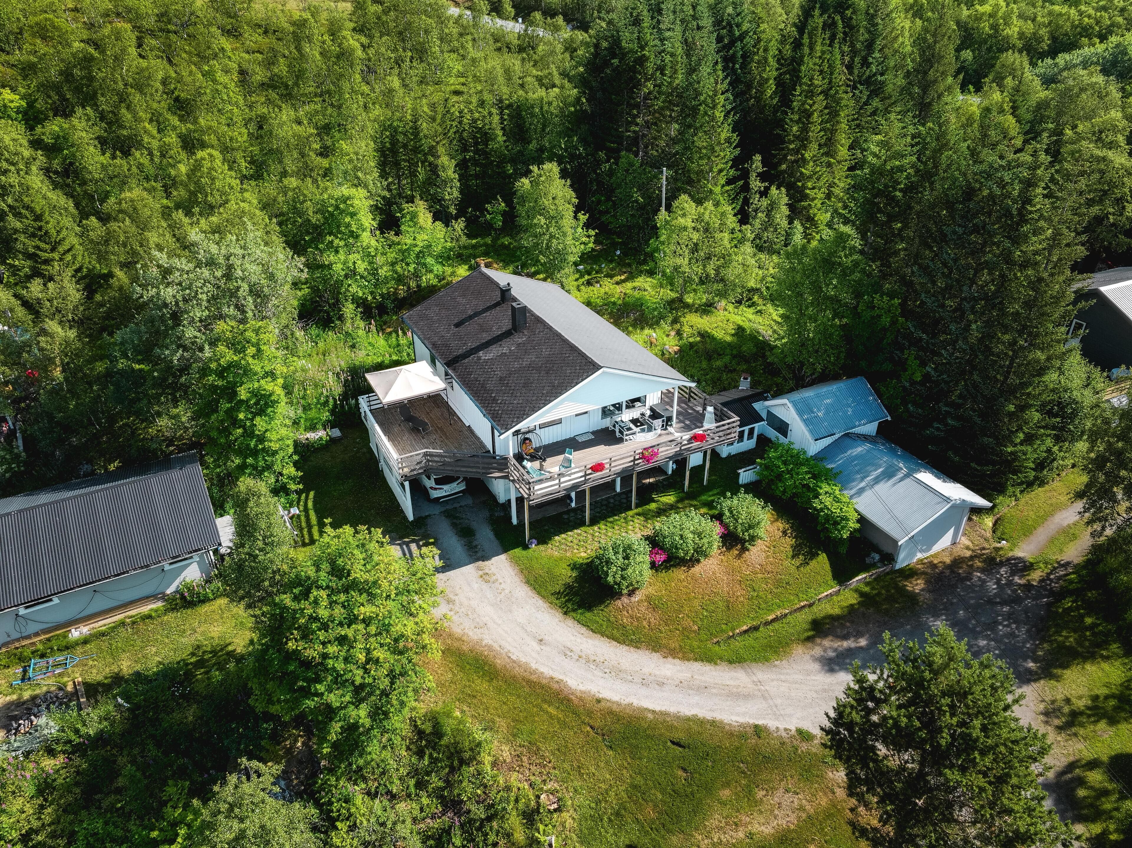 Vue aérienne d’une maison dotée d’une terrasse, entourée d’une forêt dense.