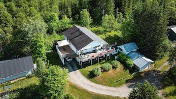 Vue aérienne d’une maison dotée d’une terrasse, entourée d’une forêt dense.