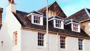 A white building with multiple windows, a door, and a small staircase leading to the entrance. - Jacobite's Retreat, 17th century cottage (Inverness)