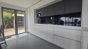 Een moderne keuken met witte kasten, een groot raam en uitzicht op de omgeving.