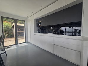 Een moderne keuken met witte kasten, een groot raam en uitzicht op de omgeving.