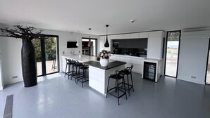 Een moderne keuken met een centraal eiland, barkrukken en een groot raam.