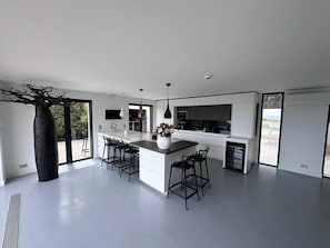 Een moderne keuken met een centraal eiland, barkrukken en een groot raam.