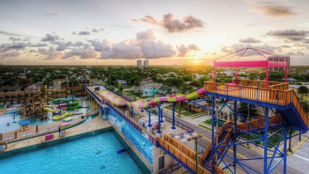 A water park with a large pool, multiple slides, and a high platform with a viewing area.