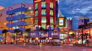 A multi-story hotel with a prominent red and yellow facade, multiple balconies, and outdoor seating areas.