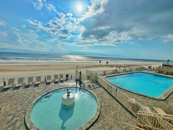 A pool area with a view of the beach and ocean.