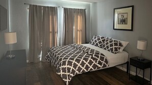 A bedroom with a bed, two bedside tables, a framed picture on the wall, and a window with curtains. - ★12Mins to Disney Theme Parks- Save 25pct Off Stay- Pool- 3BR Condo-Sleeps 10★ (Kissimmee)