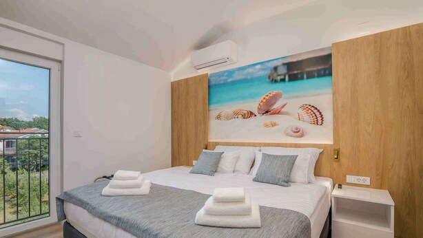 Moderni hotellihuone, jossa on suuri sänky, merinäköala ikkunasta ja puinen pääty.