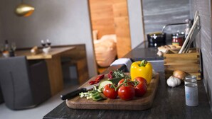A modern kitchen with a wooden cutting board, fresh vegetables, and a knife.