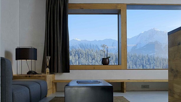 A modern living room with a large window, a sofa, a coffee table, and a lamp.