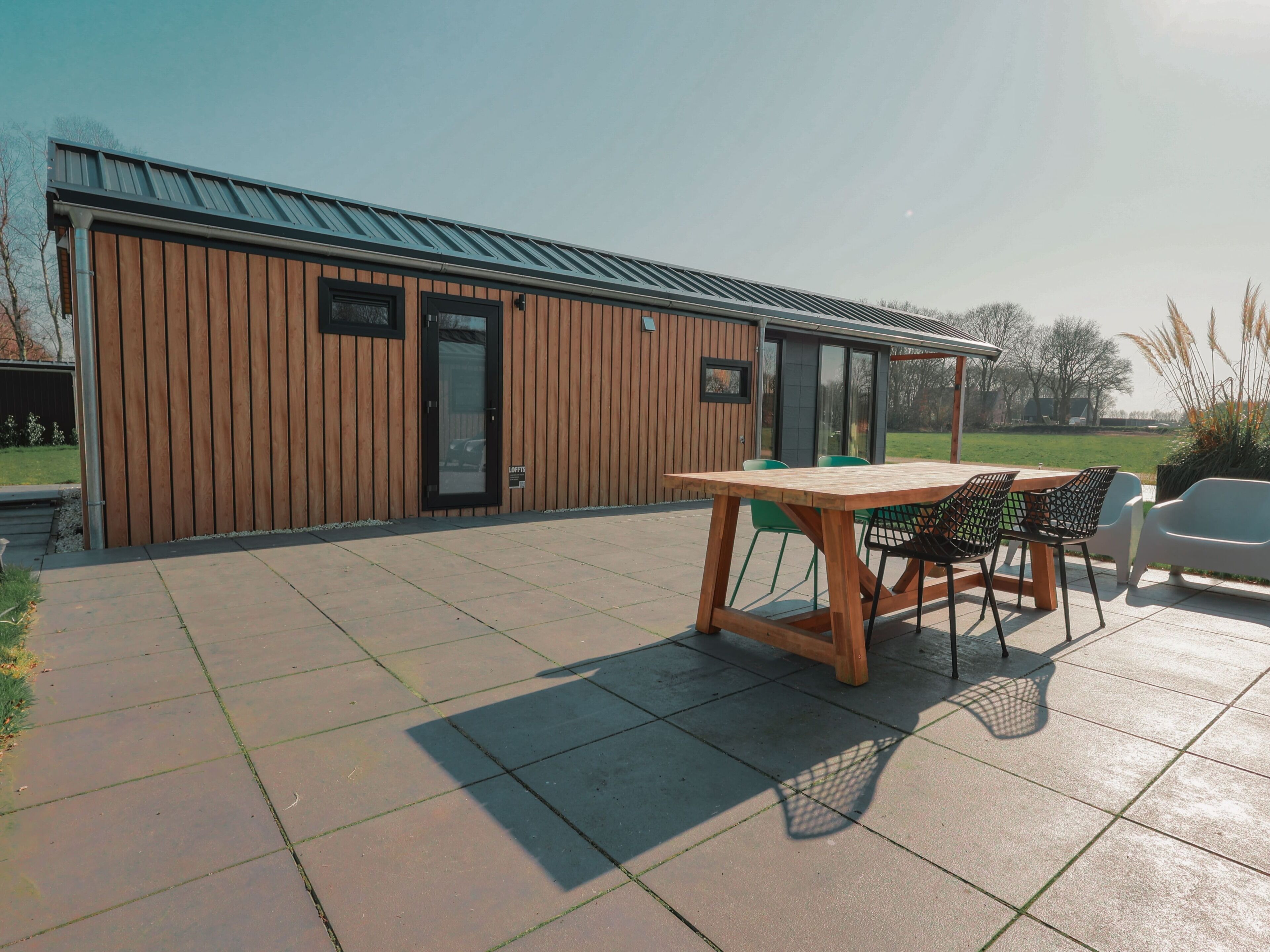 Ein modernes Gebäude mit Holzfassade und einer Terrasse, die einen Holztisch und Stühle bietet.