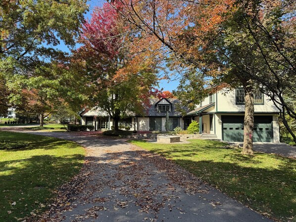 A residential area with a pathway leading to houses, surrounded by trees with autumn foliage.