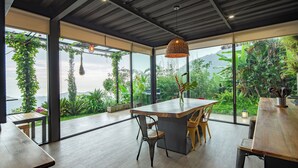 Een moderne eetruimte met een grote houten tafel, stoelen en een hanglamp.