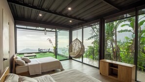 Een moderne slaapkamer met twee bedden, een hangstoel en een houten kast.
