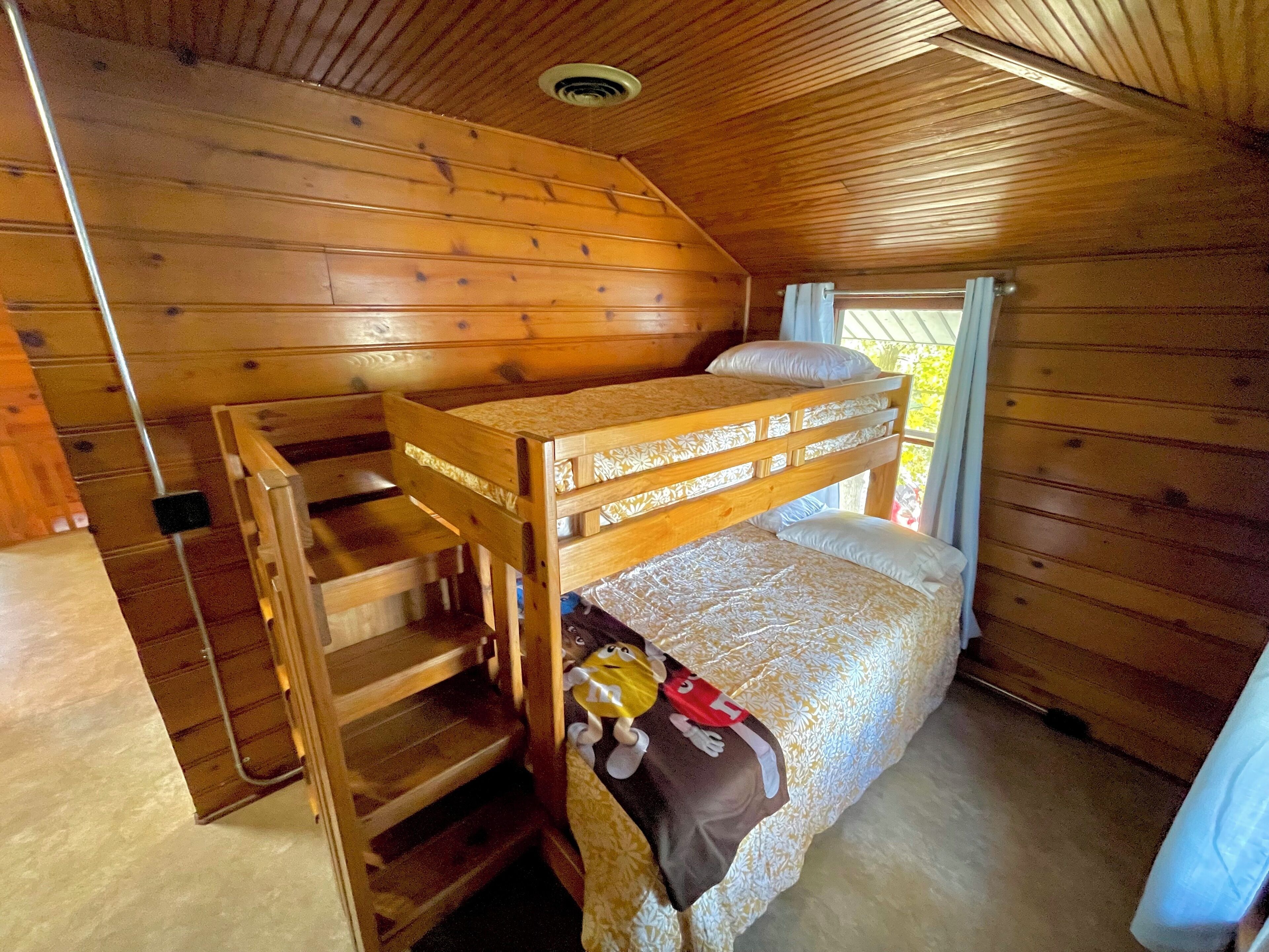 Ein Holzhütten-Zimmer mit einem Etagenbett, einem kleinen Tisch und einem Stuhl.