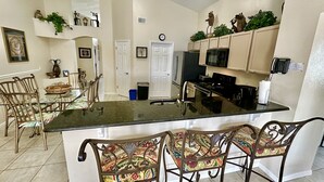 Una cocina moderna con una isla central, taburetes de bar y elementos decorativos en las paredes.