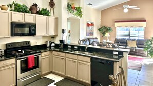 Una cocina moderna con electrodomésticos integrados, un comedor con sofá y un ventilador de techo.