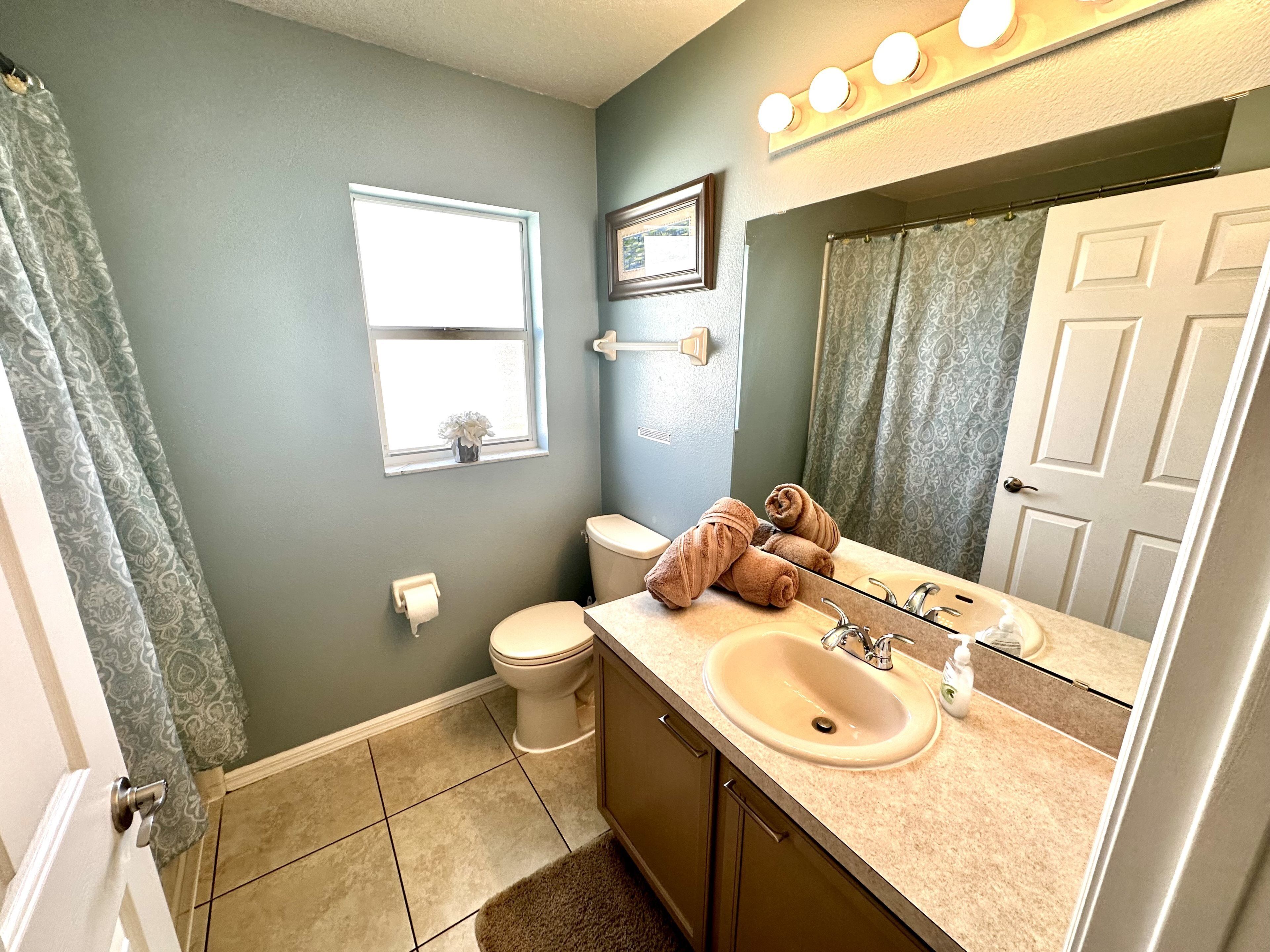 A bathroom with a toilet, sink, and mirror.