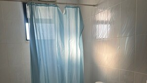 A bathroom with a shower curtain, a toilet, a sink, and a washing machine. - 2-bedroom Furnished apartment for rent in the heart of 
 jabal amman (Amman)