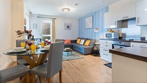 Un apartamento moderno con comedor, sala de estar con sofá y área de cocina.