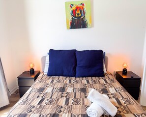 A bed with a patterned bedspread, two dark pillows, a painting of a bear, and two bedside lamps. - WS118LD - Lakeview paradise 4 Bedrooms Pool Villa (Davenport)