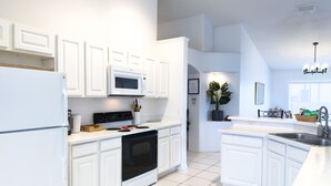 A modern kitchen with white cabinetry, a built-in microwave, a stove, and a sink.