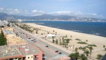 Un paisaje urbano costero con playa, una carretera y edificios.