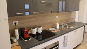 A modern kitchen with a black countertop, stainless steel sink, and wooden cabinets. - All'Antico Ulivo (Artegna)
