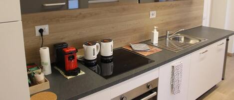 Una cocina moderna con encimera negra, pileta de acero inoxidable y armarios de madera.