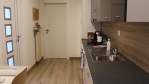 A compact kitchen with a dark countertop, stainless steel sink, and a wooden backsplash. - All'Antico Ulivo (Artegna)