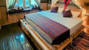 A wooden cabin bedroom with a bed, curtains, and a canopy. - Shangarh Kothi (Sainj)