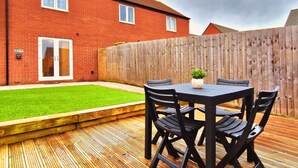 A backyard with a wooden deck, a small lawn, and a brick house. - Barn Fold House with Parking, Garden, Wi-Fi (Telford and Wrekin)