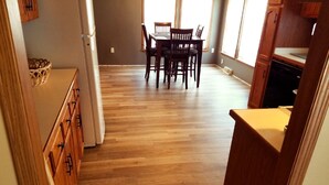 A kitchen with wooden cabinets, a dining table with chairs, and a refrigerator. - Beautiful view on lake! Enjoy 5bdrm 3 bath with 2 decks firepit and private dock (Edwards)