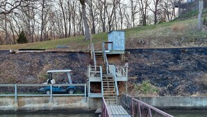 A wooden dock extending over a body of water with a small blue vehicle parked nearby. - Beautiful view on lake! Enjoy 5bdrm 3 bath with 2 decks firepit and private dock (Edwards)
