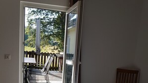 Una habitación con cama, una silla y vista a una terraza exterior.