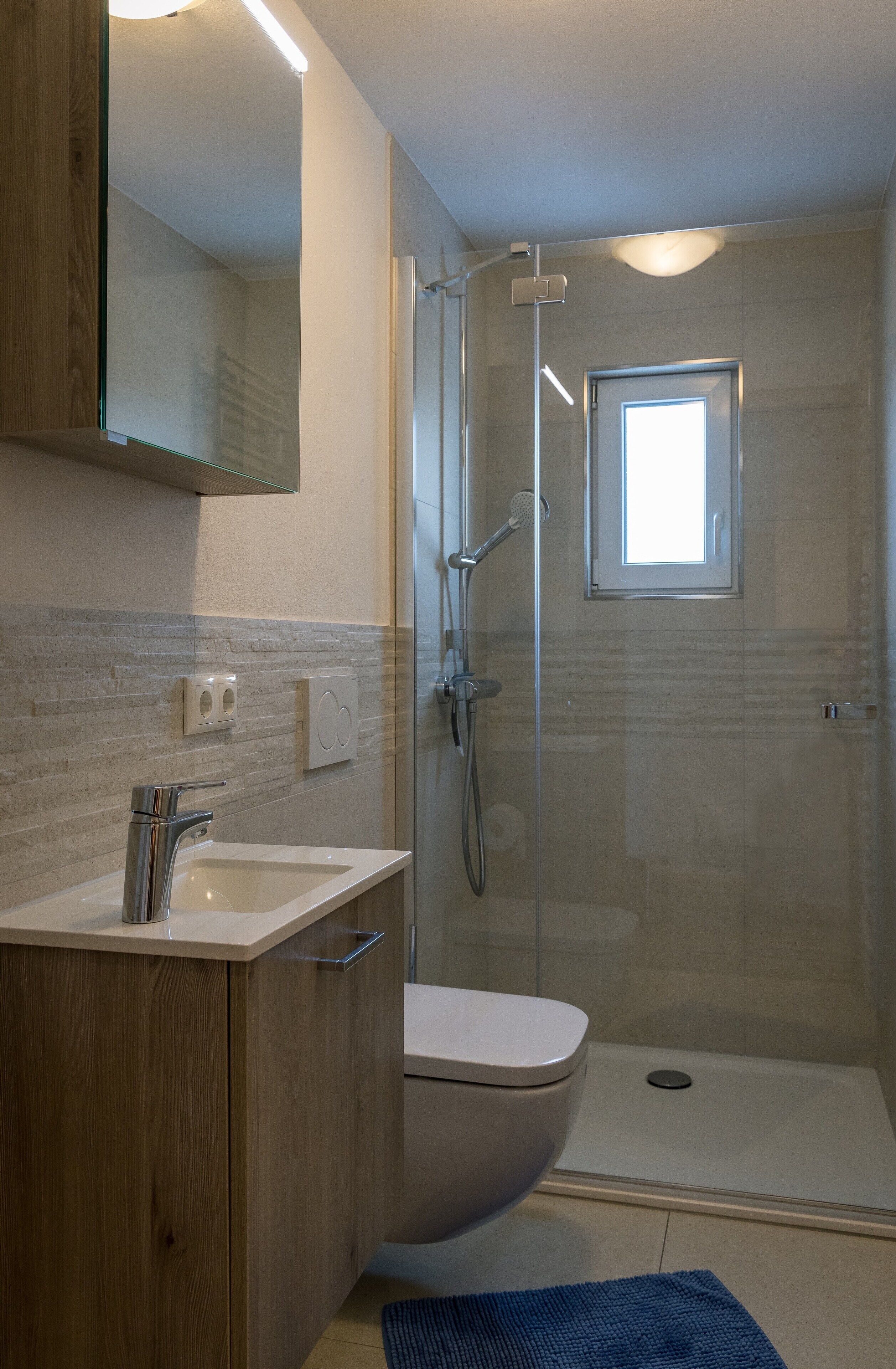 A modern bathroom with a glass-enclosed shower, a built-in sink, and a toilet.