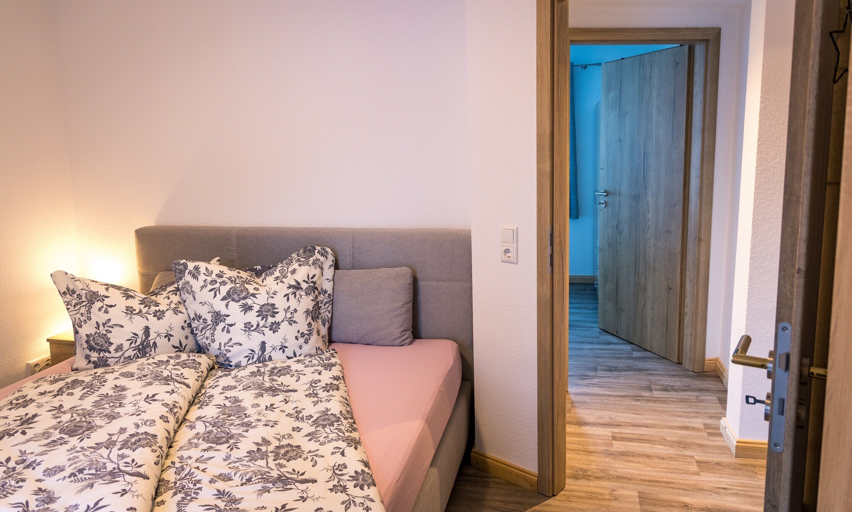 A bedroom with a bed, pillows, and a nightstand.