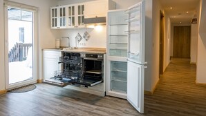 Una cocina moderna con electrodomésticos integrados, lavavajillas y un refrigerador con puertas de vidrio.
