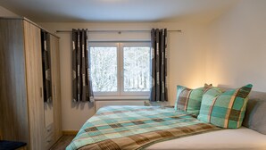 Un dormitorio con cama, armario, ventana con cortinas y una silla.