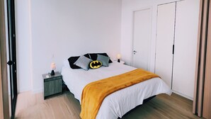 Een moderne slaapkamer met een bed, nachtkastje, bedlamp en een kledingkast.
