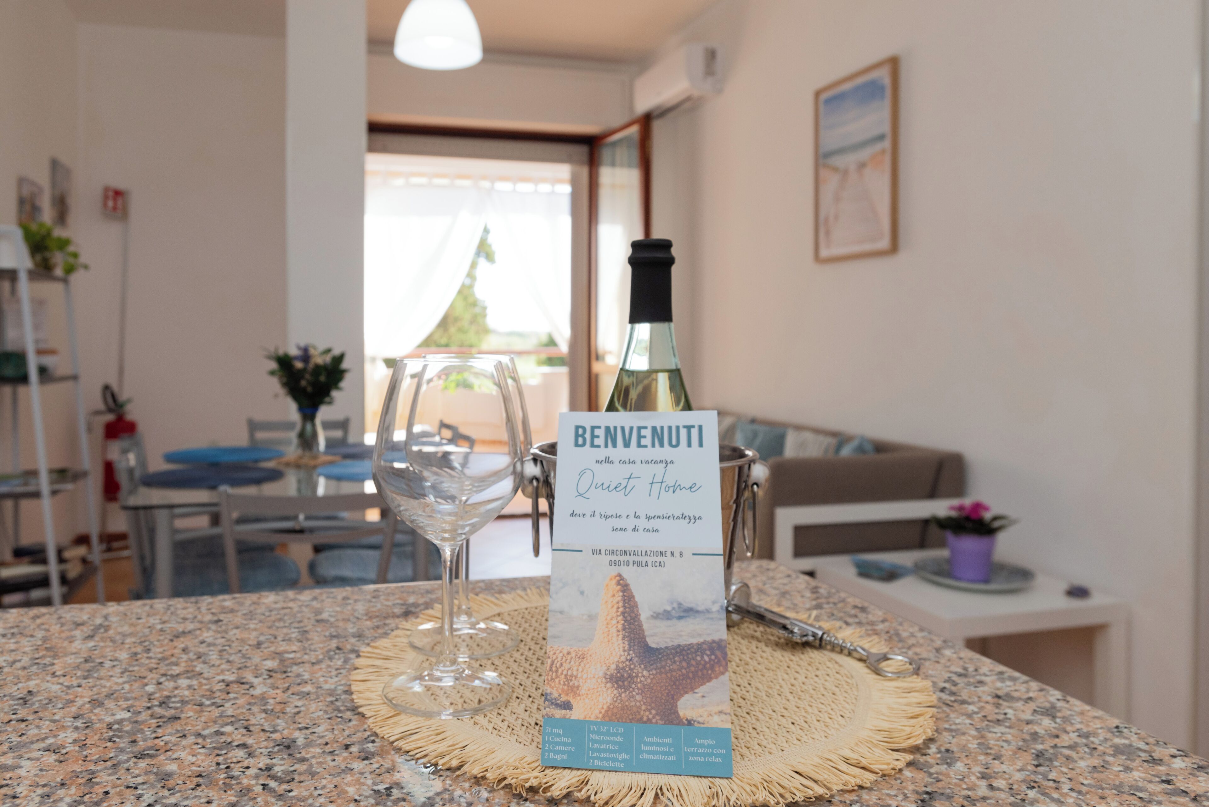 Un letrero de bienvenida con una estrella de mar sobre una mesa en una habitación con vista al exterior.