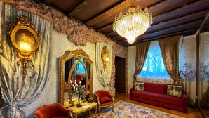 A room with a chandelier, ornate mirror, red sofa, and floral carpet. - Conacul Coroanei Luxury Boutique (Bucharest)