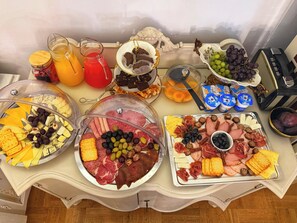 Ein reichhaltiges Buffet mit verschiedenen Speisen, darunter Fleisch, Käse, Obst und Getränke.