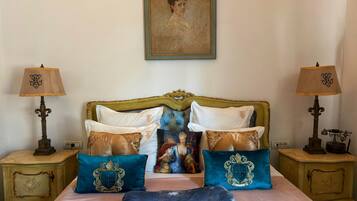 A bedroom with a bed, pillows, a nightstand, a lamp, and a painting on the wall.